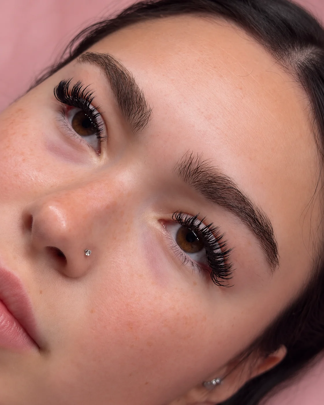 Close-up of a client's soft lash extensions and brown eyes